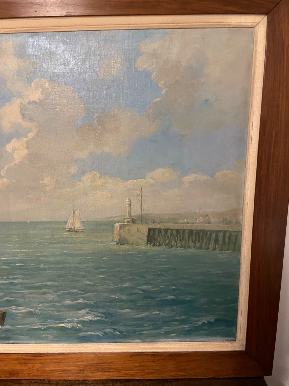 An early 20th-century oil painting on canvas depicting fishermen and sailing vessels at a stone harbour quay, set within a wide wooden frame. View II