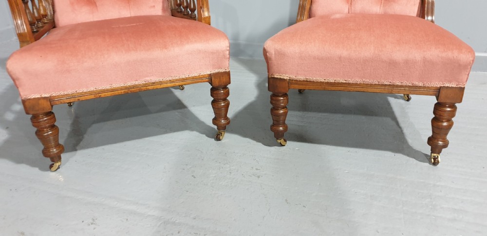 A pair of late Victorian carved oak chairs featuring button-tufted rose pink velvet upholstery and turned legs on brass castors. View IV