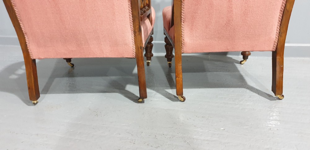 A pair of late Victorian carved oak chairs featuring button-tufted rose pink velvet upholstery and turned legs on brass castors. View VII