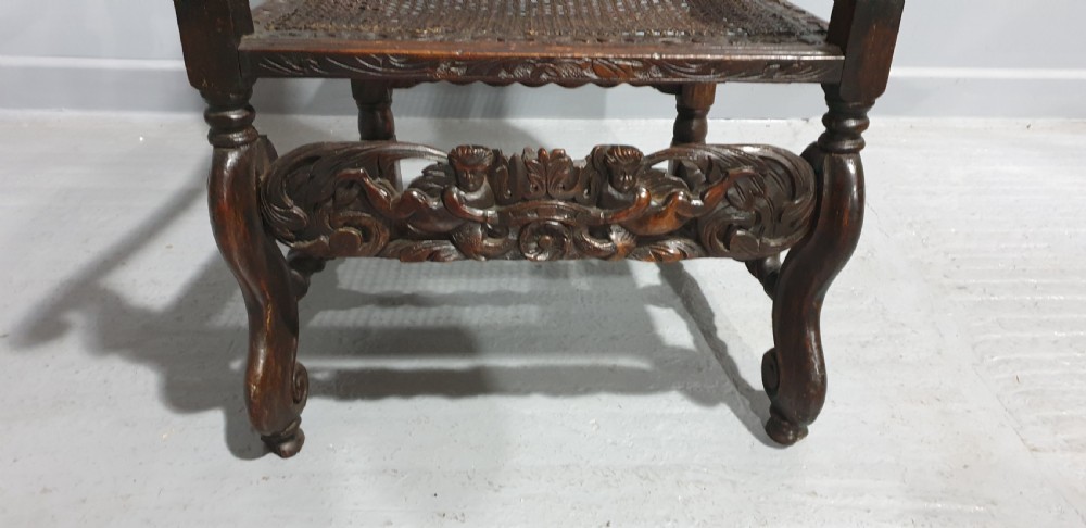 A high-backed dark oak carver chair featuring an oval cane backrest, barley twist posts, hand-carved cresting, and a patterned seat cushion. View VIII