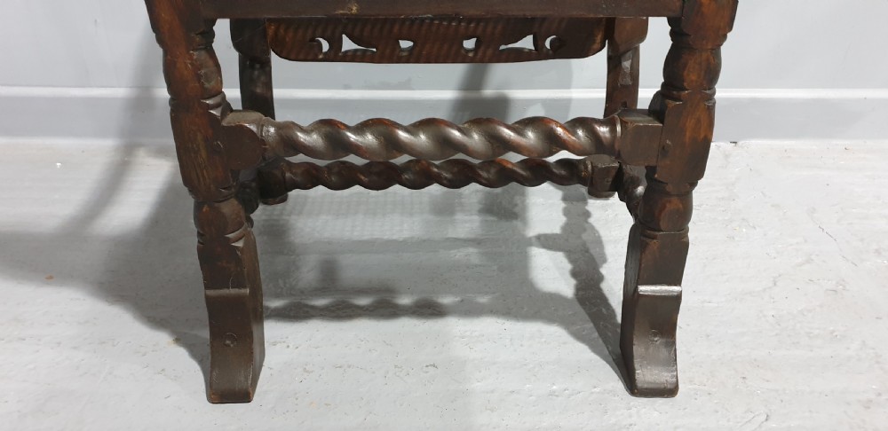 A high-backed dark oak carver chair featuring an oval cane backrest, barley twist posts, hand-carved cresting, and a patterned seat cushion. View XIII