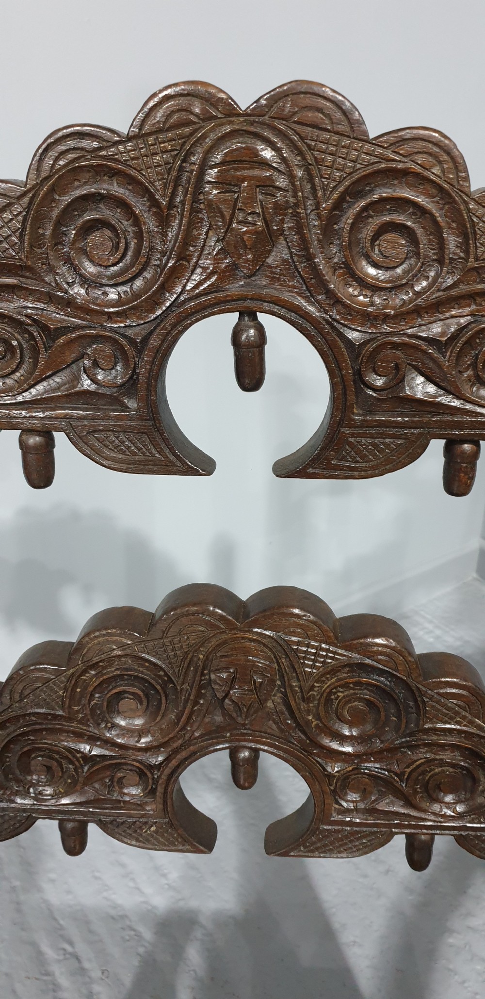 A pair of dark carved oak carver armchairs featuring decorative scrolled backrests, turned legs, bobbin stretchers, and leather seats. View II