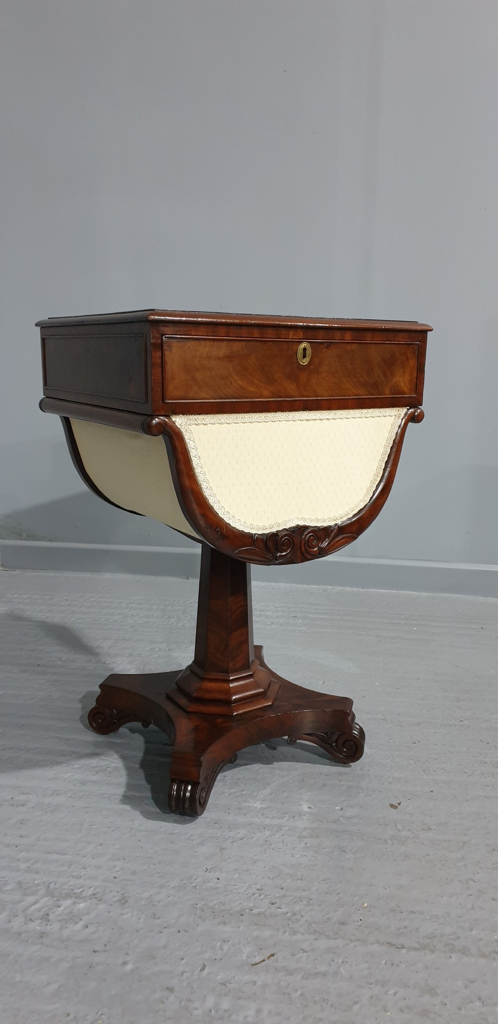 A William IV mahogany work box table featuring a single drawer over a cream fabric-lined storage well, supported on a central pedestal and quadform base with scroll feet. View II