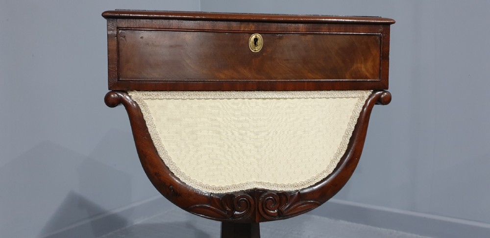 A William IV mahogany work box table featuring a single drawer over a cream fabric-lined storage well, supported on a central pedestal and quadform base with scroll feet. View IV