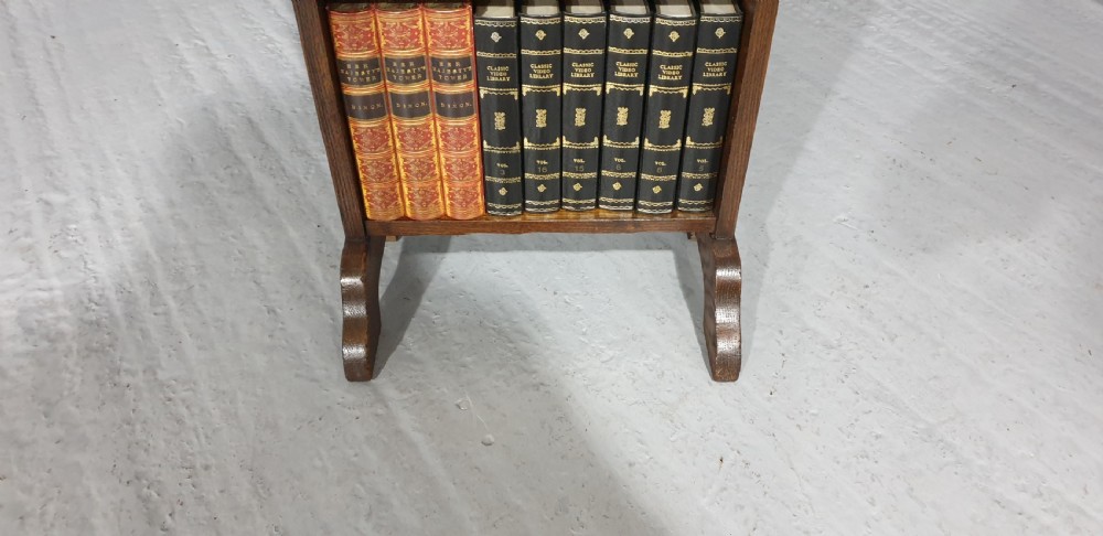 A slim floor-standing solid oak open bookcase featuring four tiered shelves filled with colourful antique books. View IV