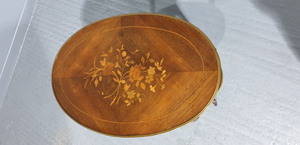 An oval French-style two-tier occasional table featuring floral marquetry inlay, slender cabriole legs, and gilt-bronze mounts. View V