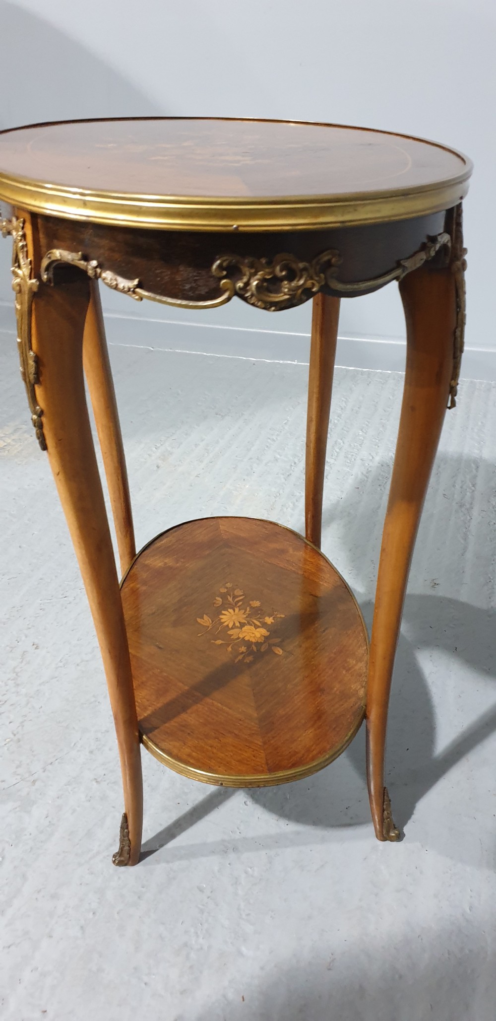 An oval French-style two-tier occasional table featuring floral marquetry inlay, slender cabriole legs, and gilt-bronze mounts. View VI