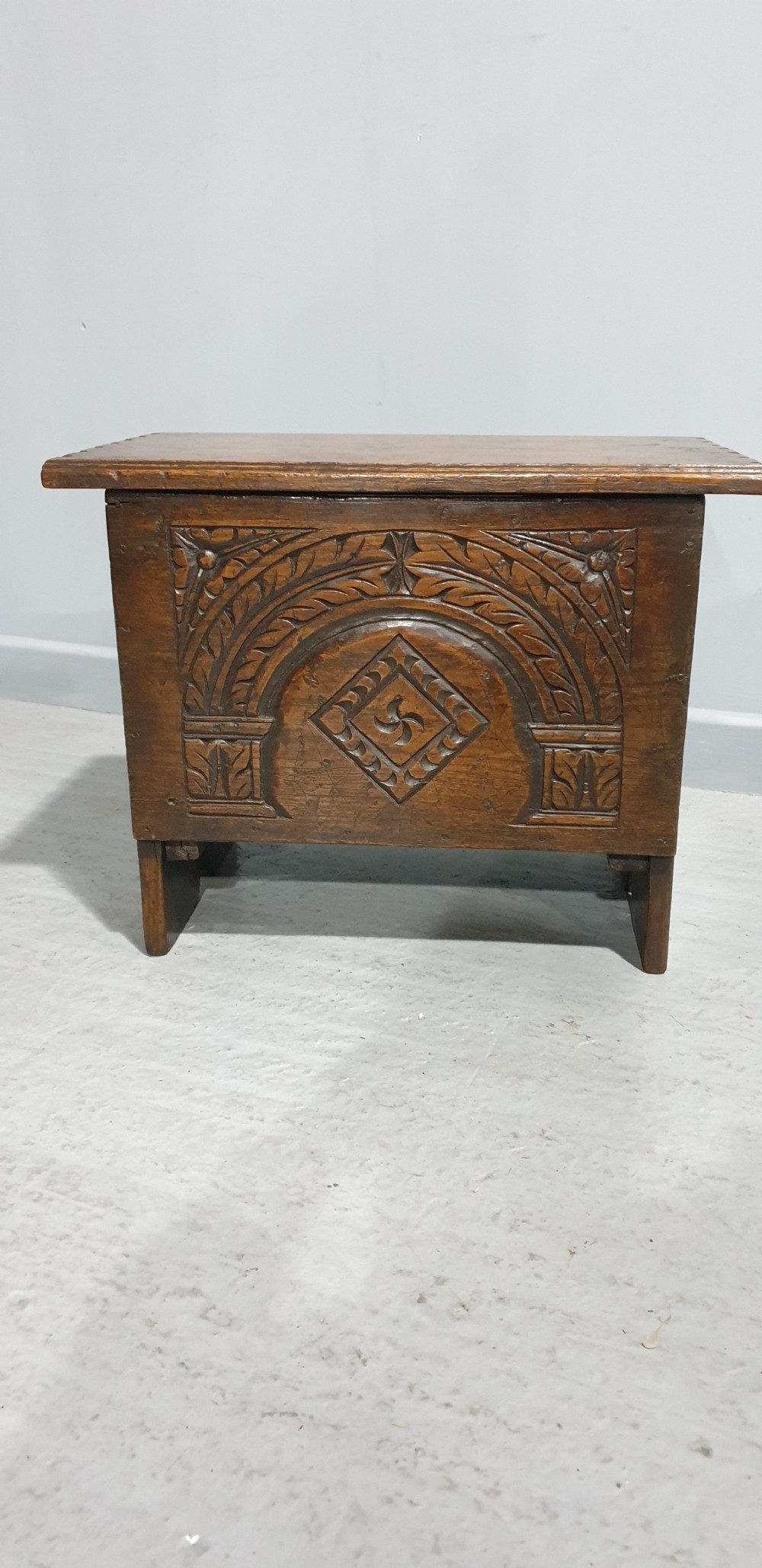 A small dark oak coffer featuring detailed arcaded and lozenge carved motifs on the front panel. View II