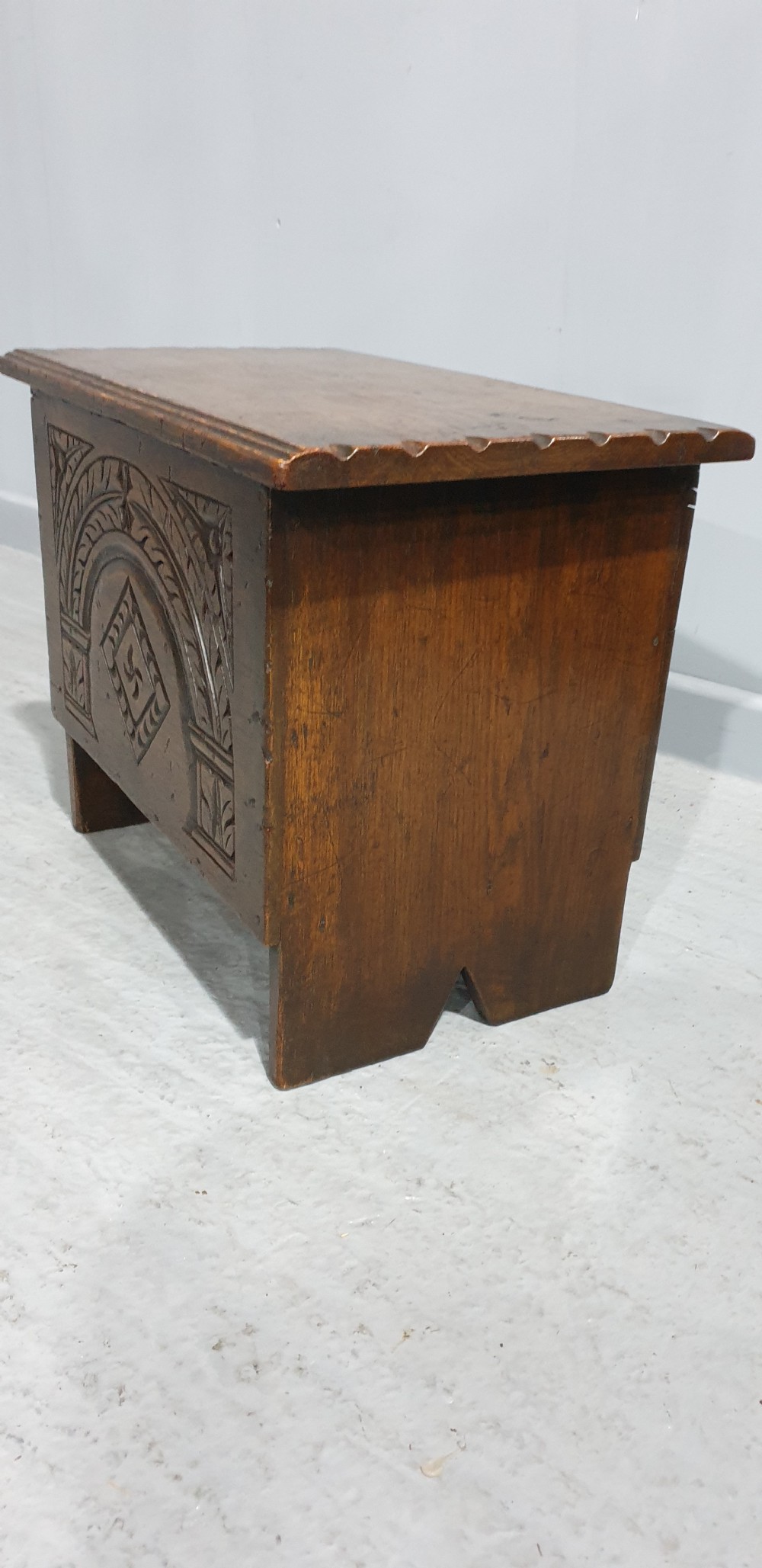 A small dark oak coffer featuring detailed arcaded and lozenge carved motifs on the front panel. View V