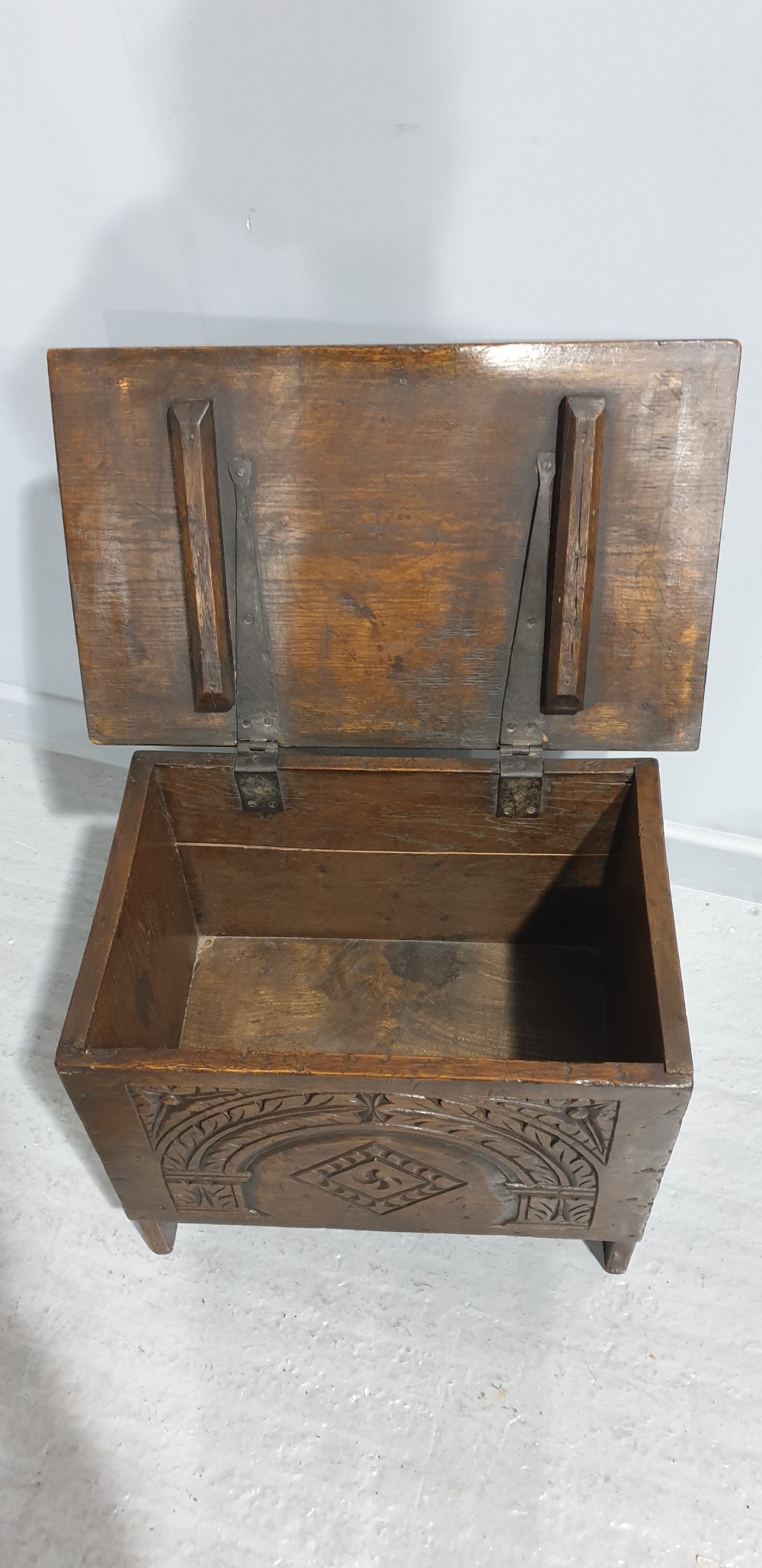 A small dark oak coffer featuring detailed arcaded and lozenge carved motifs on the front panel. View VIII