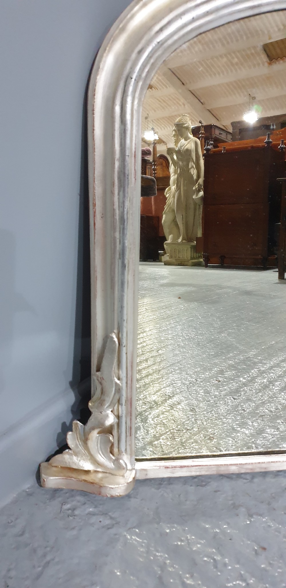 A Victorian silvered overmantel mirror featuring an arched top and moulded scroll feet at the base. View III