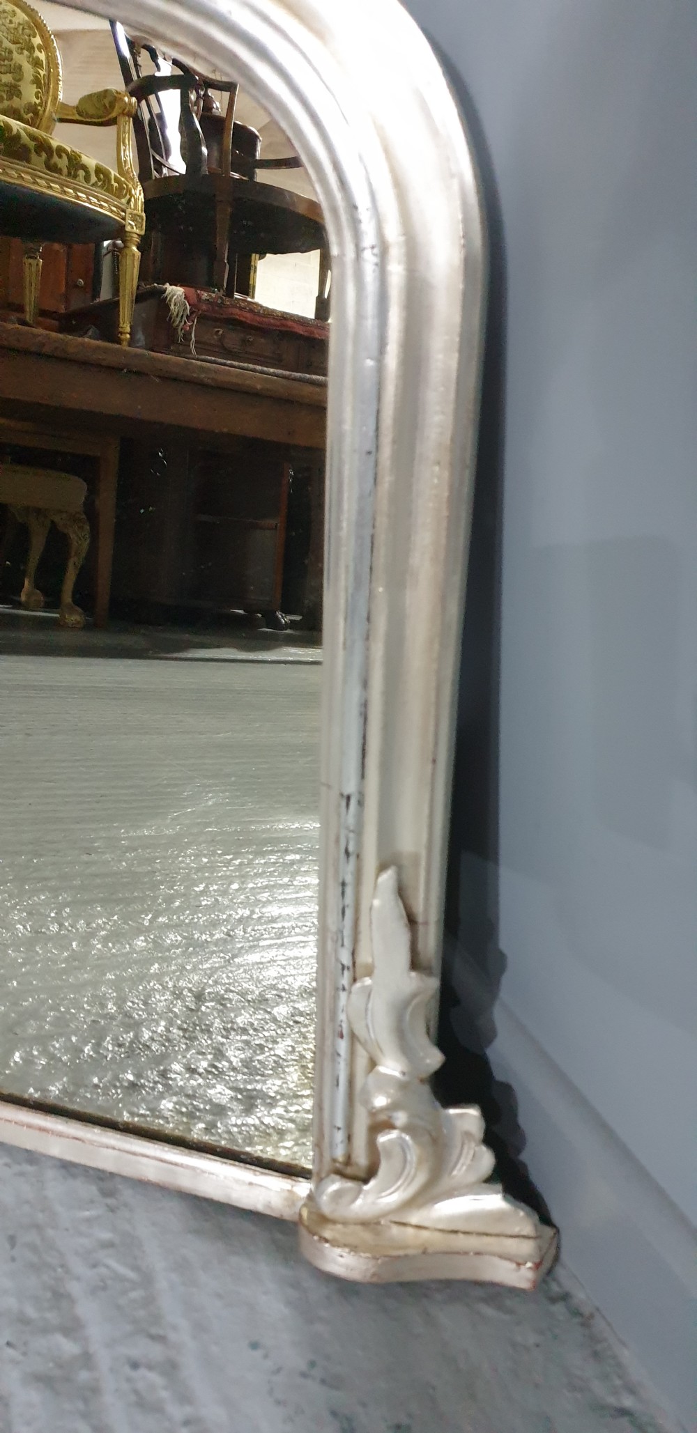 A Victorian silvered overmantel mirror featuring an arched top and moulded scroll feet at the base. View V