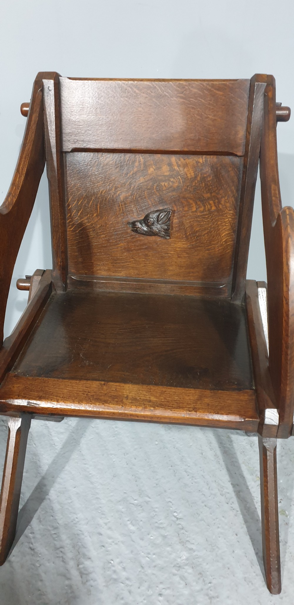 A Victorian dark oak Glastonbury chair with an X-frame base, shaped armrests, and a carved central leaf motif on the panelled back. View III