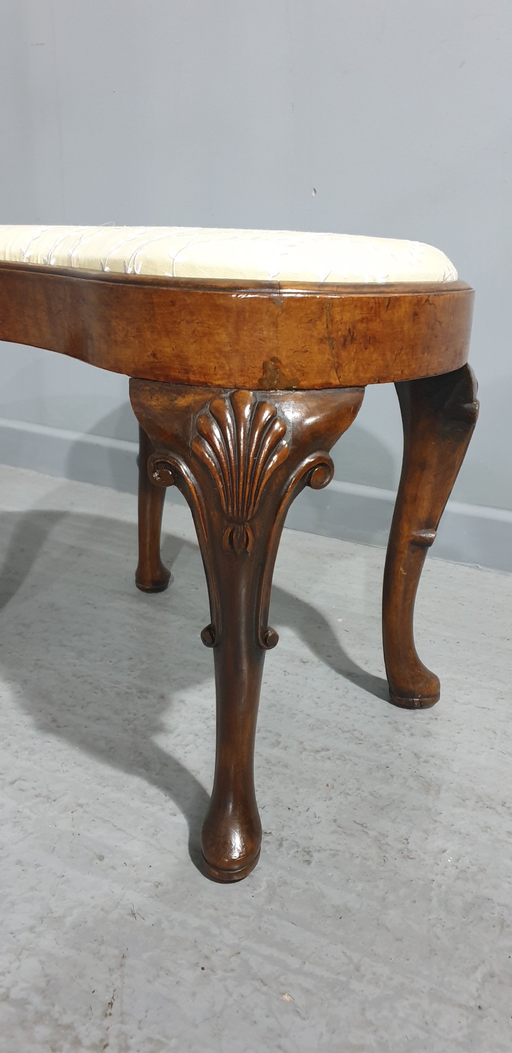A Victorian kidney-shaped stool crafted from burr walnut featuring carved cabriole legs and cream patterned upholstery. View III