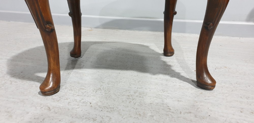A Victorian kidney-shaped stool crafted from burr walnut featuring carved cabriole legs and cream patterned upholstery. View IV