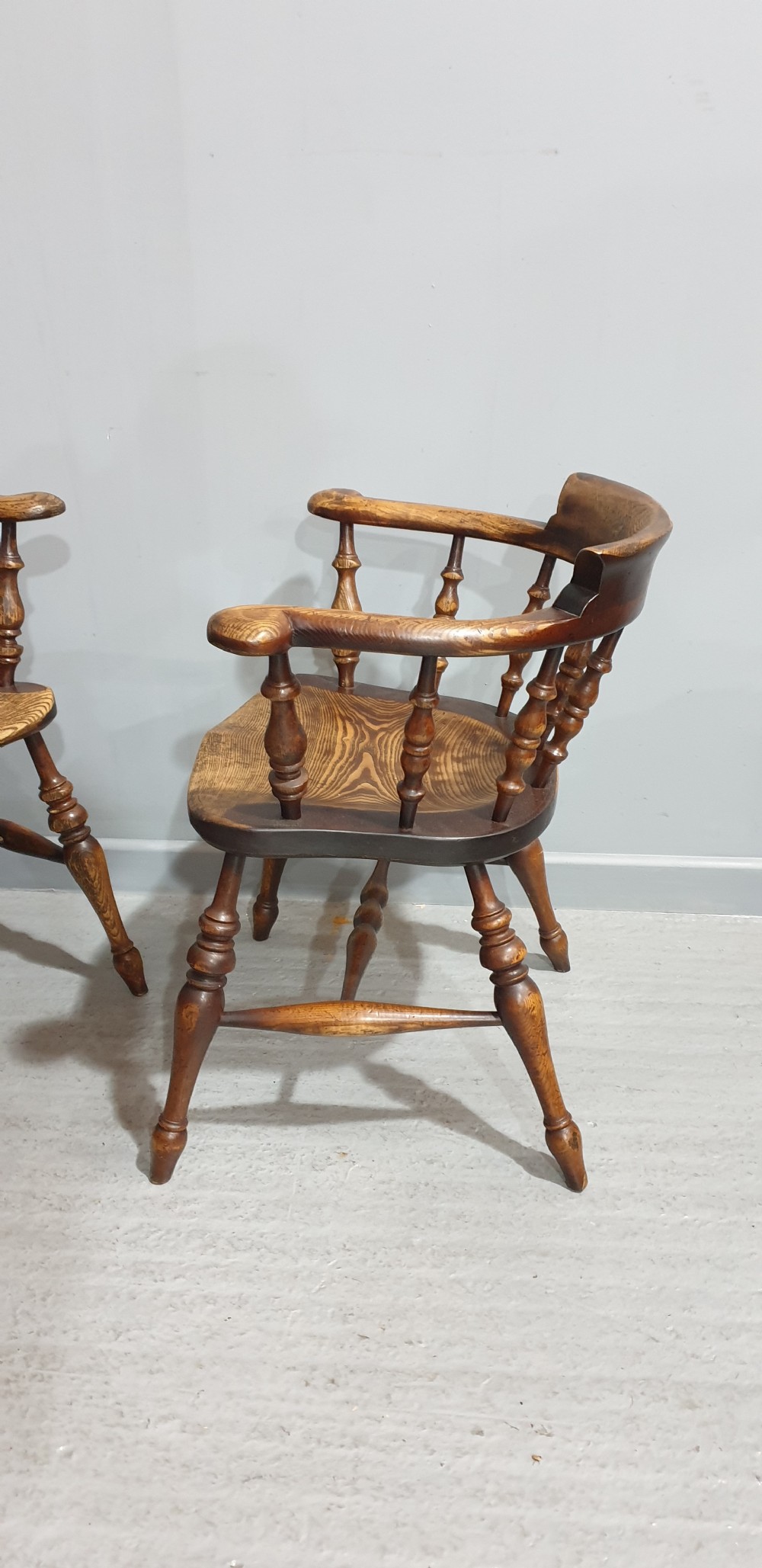 A set of ten antique English elm smokers bow armchairs featuring horseshoe crest rails, turned spindles, shaped saddle seats, and turned legs. View VI