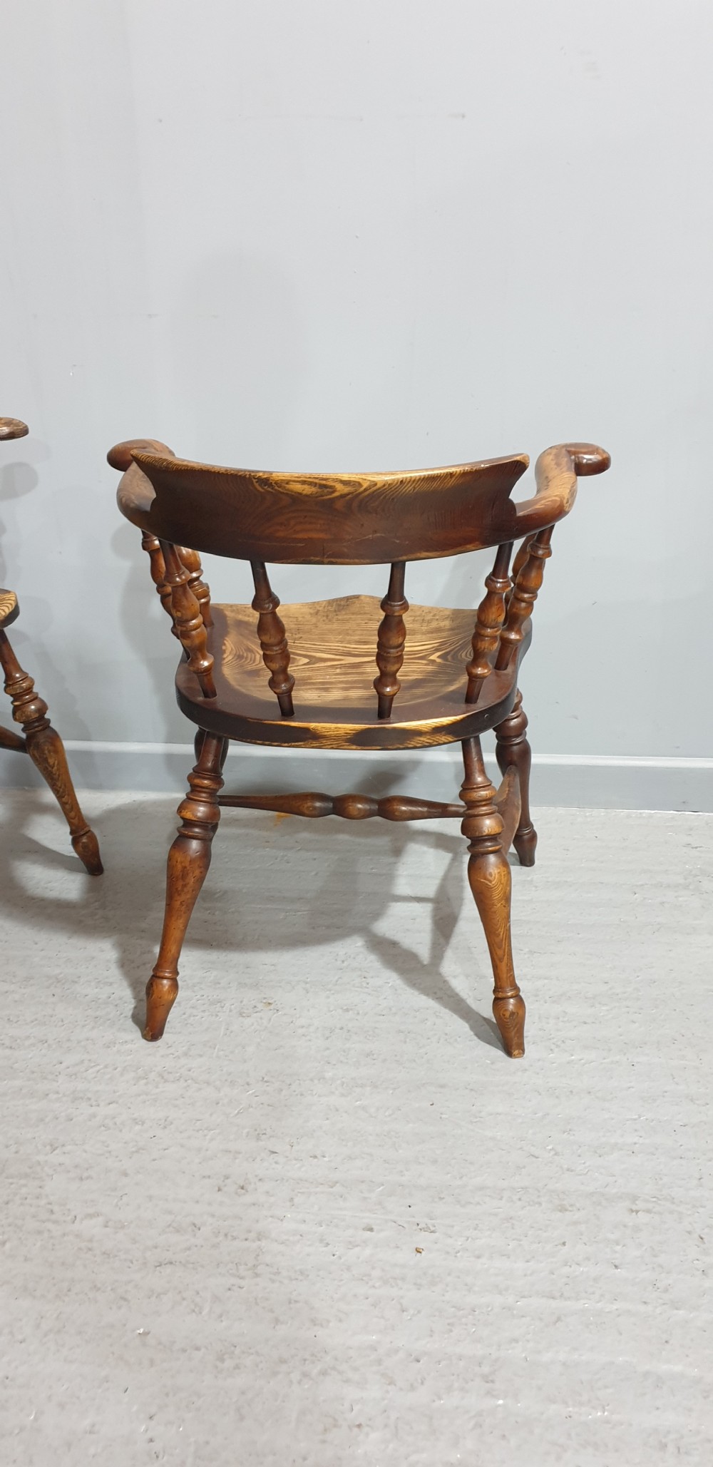 A set of ten antique English elm smokers bow armchairs featuring horseshoe crest rails, turned spindles, shaped saddle seats, and turned legs. View VIII