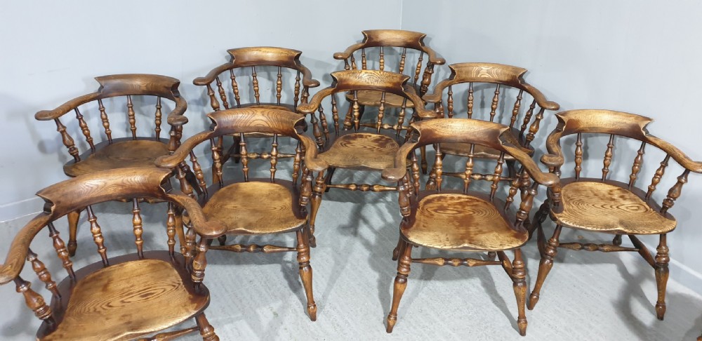A set of ten antique English elm smokers bow armchairs featuring horseshoe crest rails, turned spindles, shaped saddle seats, and turned legs. View IX