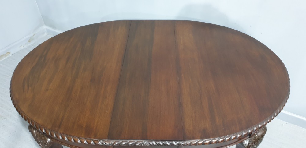 An oval Victorian mahogany extending dining table with carved cabriole legs terminating in ball and claw feet. View IV