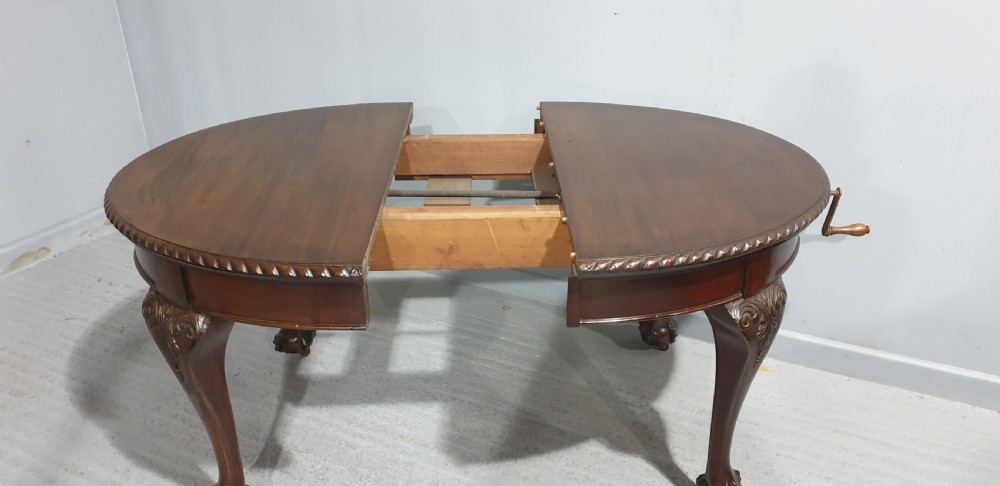 An oval Victorian mahogany extending dining table with carved cabriole legs terminating in ball and claw feet. View IX