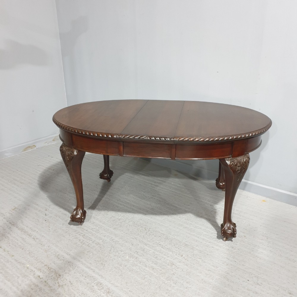 An oval Victorian mahogany extending dining table with carved cabriole legs terminating in ball and claw feet.