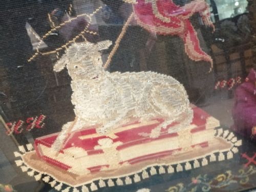 fig 1. An early nineteenth-century framed raised woolwork picture depicting the Agnus Dei resting on a red book within a floral border.