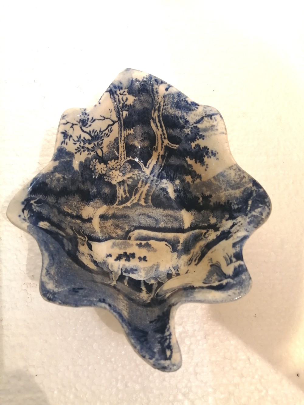 A leaf-shaped Georgian porcelain dish featuring a cobalt blue underglaze transfer print depicting cattle beneath trees.