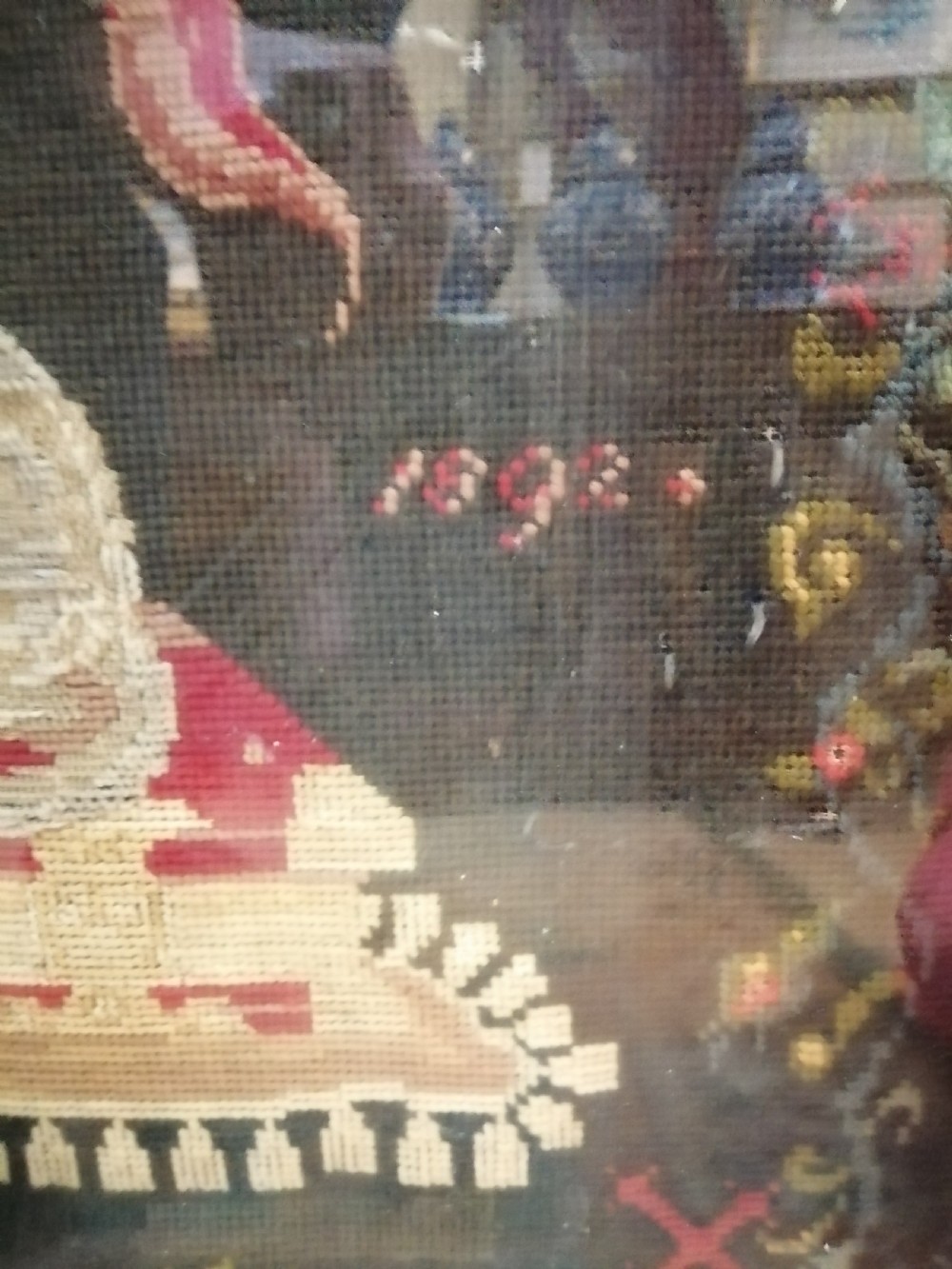 An early nineteenth-century framed raised woolwork picture depicting the Agnus Dei resting on a red book within a floral border. View III