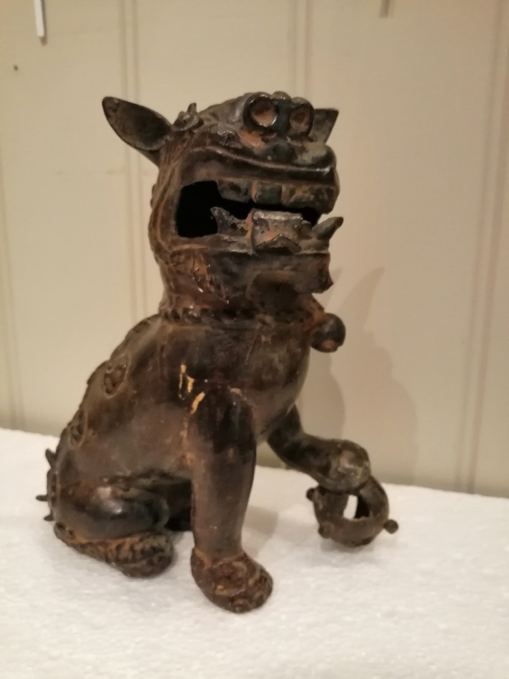 An 18th-century dark patinated hollow bronze Japanese foo dog sculpture seated on its hind legs with one paw resting on a sphere.