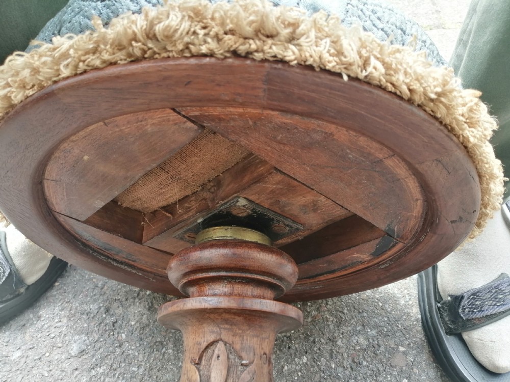 A 19th-century Victorian walnut rise and fall piano stool featuring a circular light blue patterned upholstered seat with fringed trim set on a carved tripod base. View VI