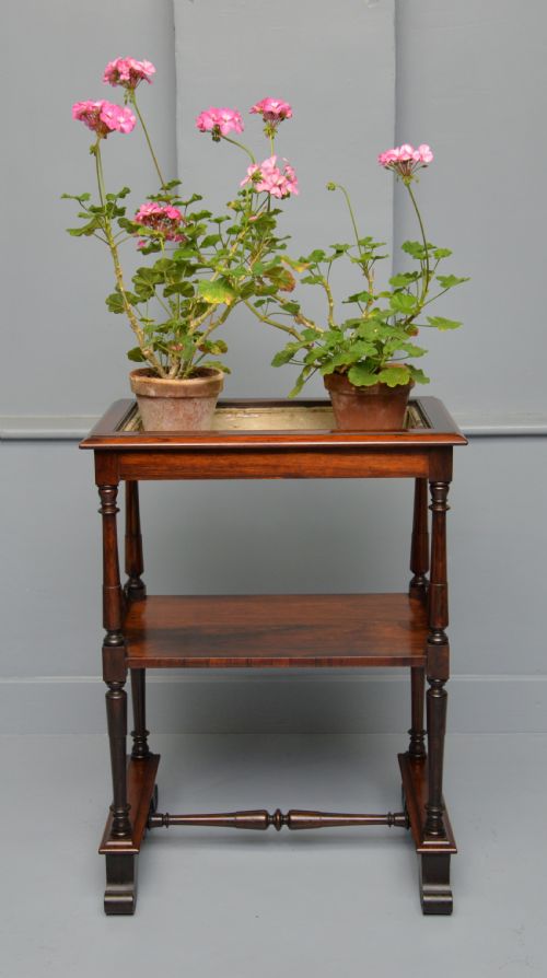 fig 3. A dark William IV rosewood plant stand with a recessed upper tray, turned support posts, a lower shelf with carved scrollwork, and scroll feet.