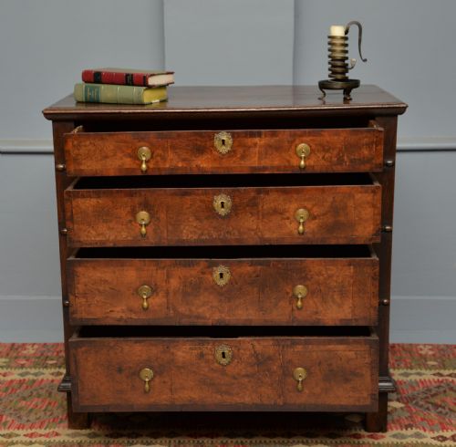 fig 2. A William and Mary walnut and yew wood chest of four drawers featuring brass teardrop handles and decorative bead moulding.