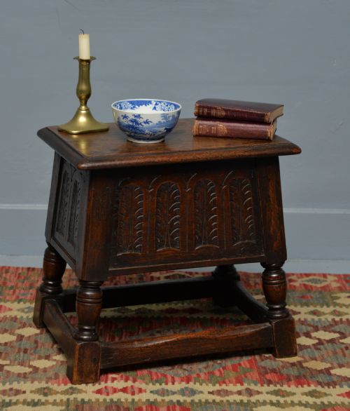 fig 1. A dark oak box stool featuring carved arched panels, turned baluster legs, and a rectangular top.