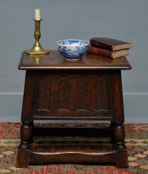 fig 2. A dark oak box stool featuring carved arched panels, turned baluster legs, and a rectangular top.