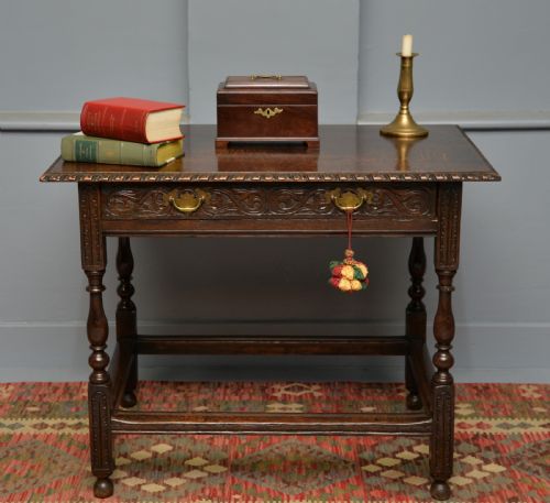 fig 1. A dark carved oak side table featuring a single scroll-carved frieze drawer, turned legs, and a lower stretcher frame.