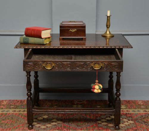 fig 2. A dark carved oak side table featuring a single scroll-carved frieze drawer, turned legs, and a lower stretcher frame.