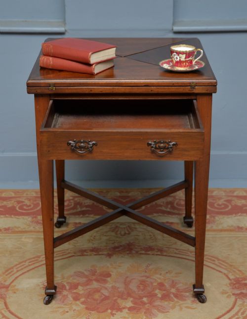 fig 2. An antique mahogany envelope card table featuring four triangular top flaps, a single drawer with brass drop handles, and tapered legs joined by an X-shaped stretcher.