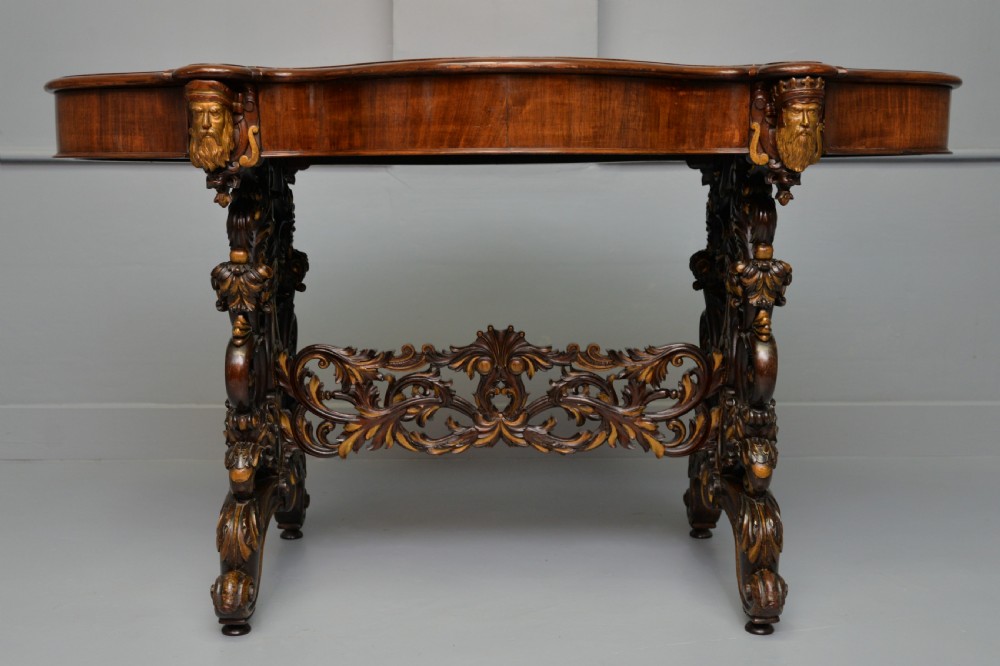 A 19th-century dark carved mahogany centre table featuring a shaped top, parcel-gilt mask corner details, and intricate openwork scroll legs. View II