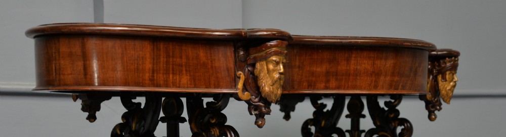 A 19th-century dark carved mahogany centre table featuring a shaped top, parcel-gilt mask corner details, and intricate openwork scroll legs. View VII
