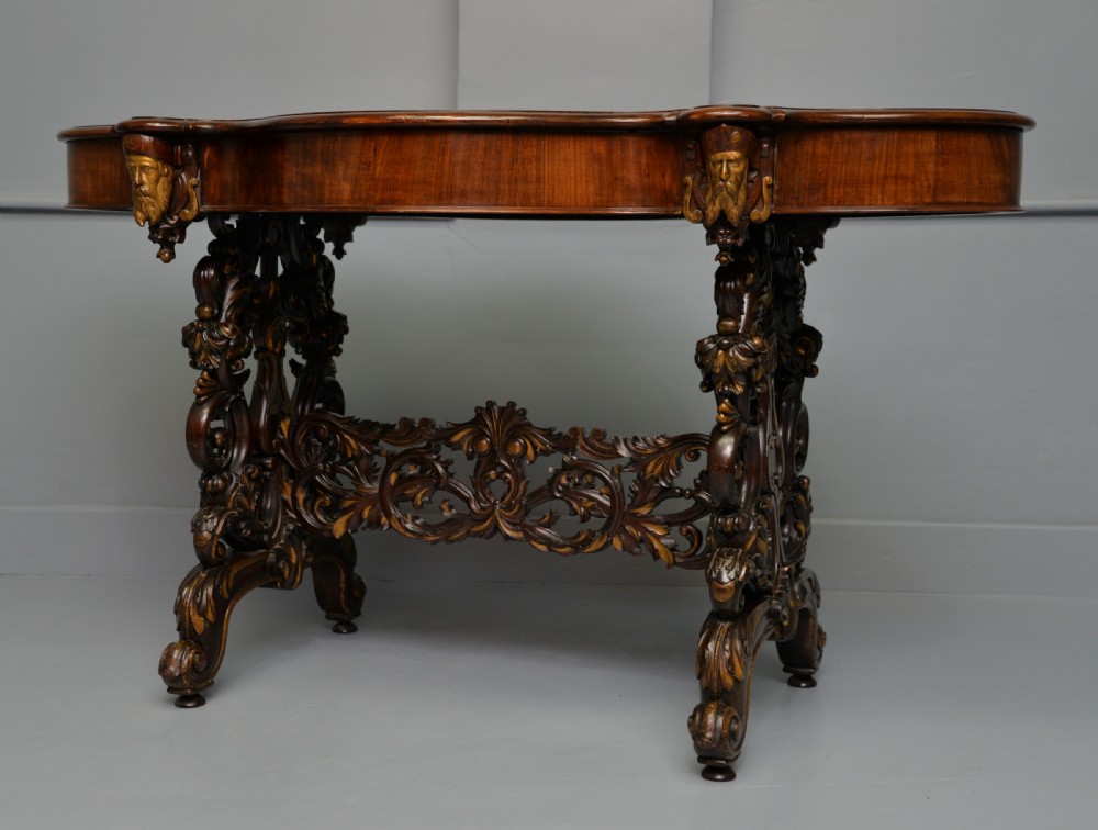 A 19th-century dark carved mahogany centre table featuring a shaped top, parcel-gilt mask corner details, and intricate openwork scroll legs. View XIII