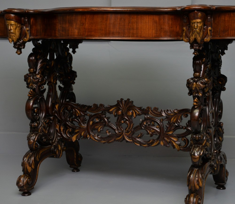 A 19th-century dark carved mahogany centre table featuring a shaped top, parcel-gilt mask corner details, and intricate openwork scroll legs. View XIV