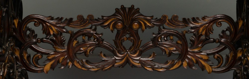 A 19th-century dark carved mahogany centre table featuring a shaped top, parcel-gilt mask corner details, and intricate openwork scroll legs. View XV