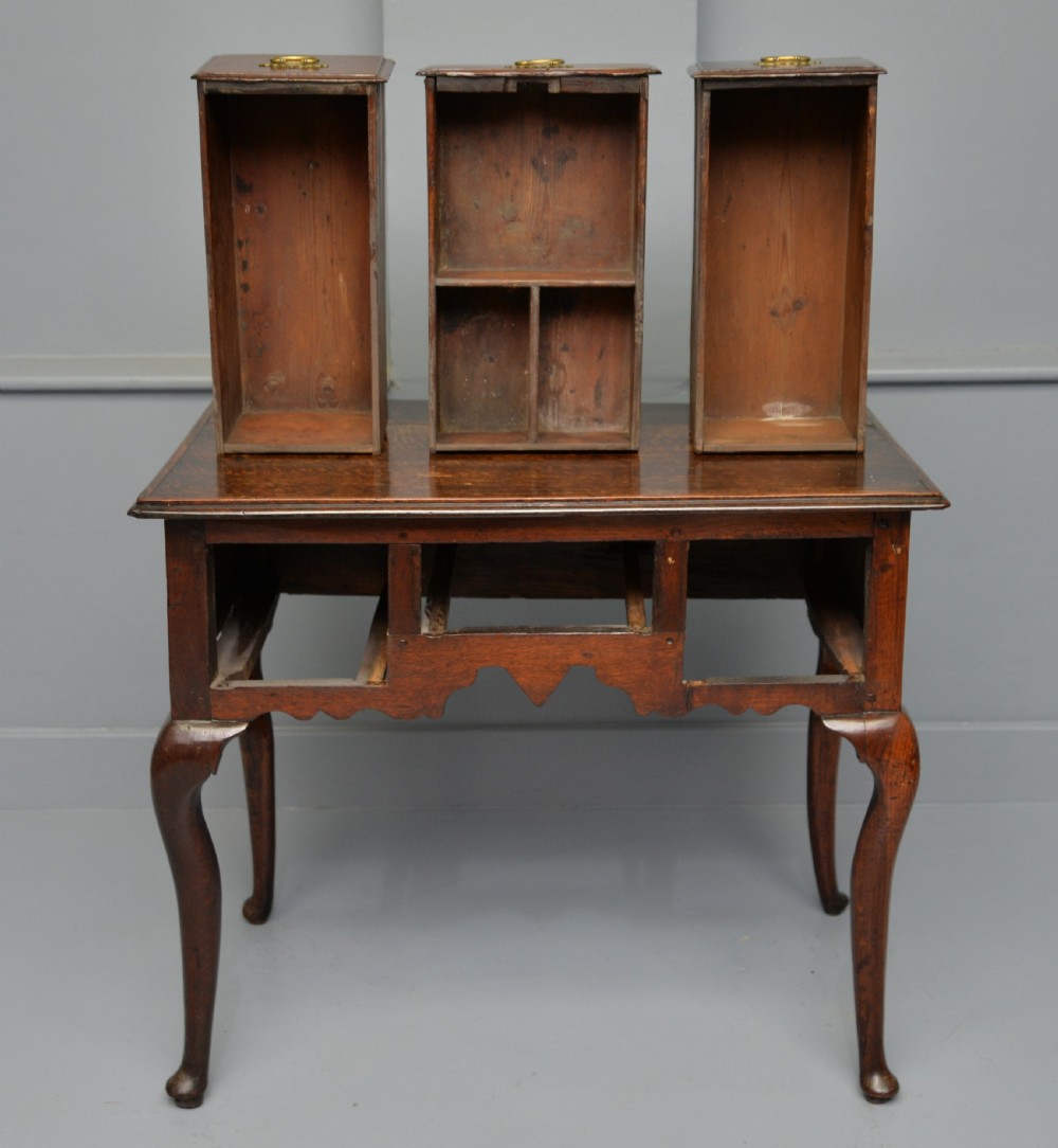 An early eighteenth-century oak lowboy featuring three drawers with brass handles, a scalloped apron, and four cabriole legs with pad feet. View XIX
