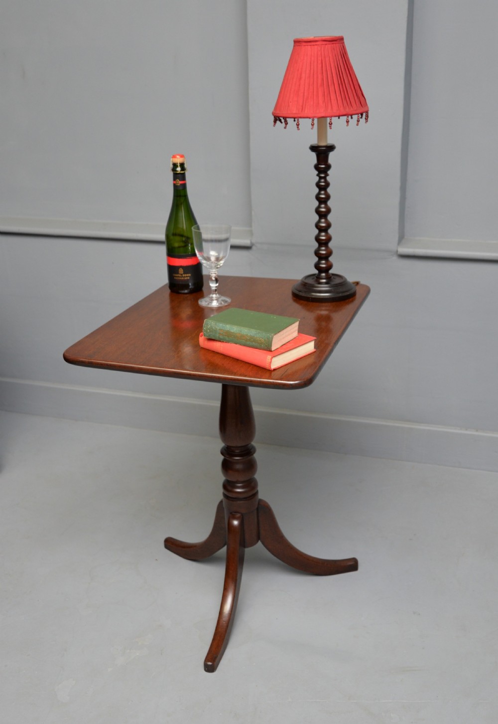 A Victorian solid mahogany wine table with a rectangular rounded top, a central turned pedestal, and a tripod base. View VI