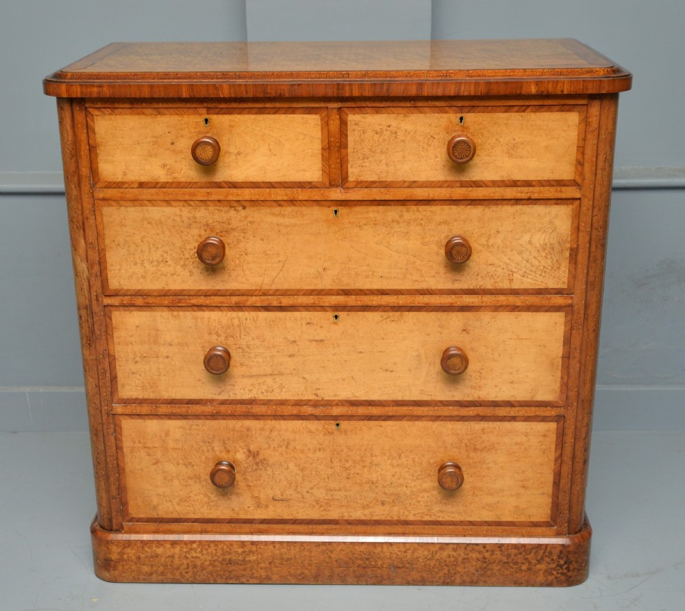 A Victorian satinwood chest of drawers featuring two small upper drawers above three full-width drawers with turned rosette knobs and a plinth base. View V