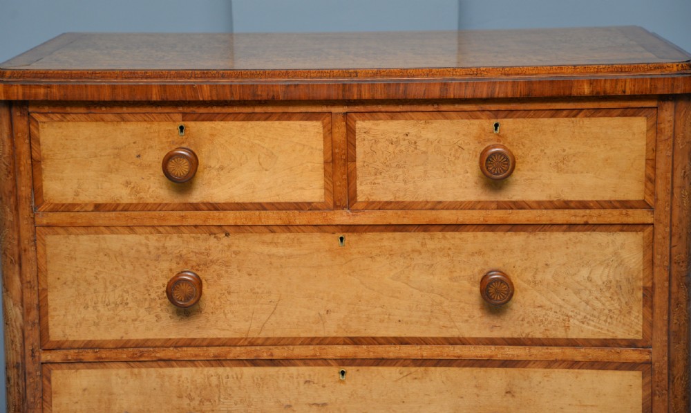 A Victorian satinwood chest of drawers featuring two small upper drawers above three full-width drawers with turned rosette knobs and a plinth base. View VI