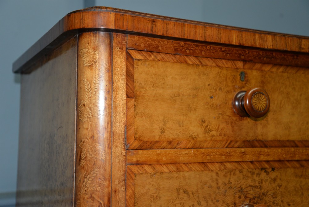 A Victorian satinwood chest of drawers featuring two small upper drawers above three full-width drawers with turned rosette knobs and a plinth base. View X