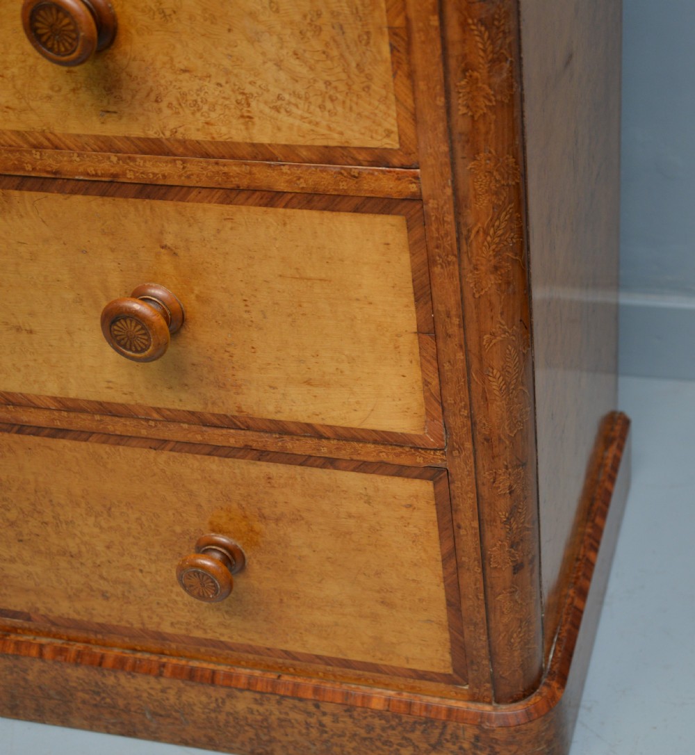 A Victorian satinwood chest of drawers featuring two small upper drawers above three full-width drawers with turned rosette knobs and a plinth base. View XV