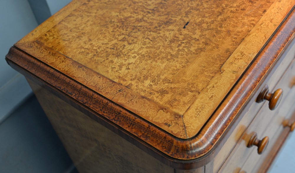 A Victorian satinwood chest of drawers featuring two small upper drawers above three full-width drawers with turned rosette knobs and a plinth base. View XX