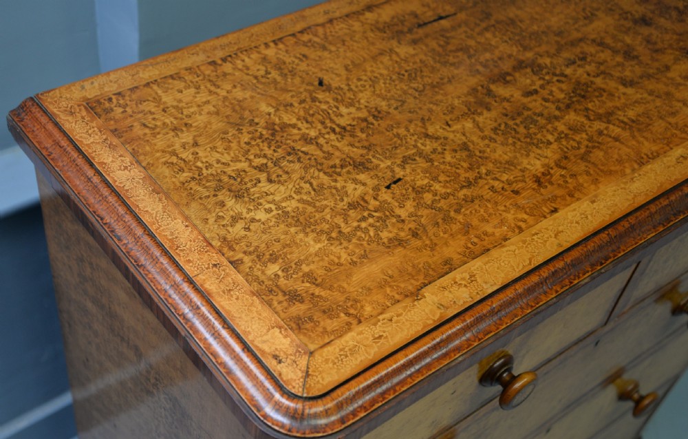A Victorian satinwood chest of drawers featuring two small upper drawers above three full-width drawers with turned rosette knobs and a plinth base. View XXII
